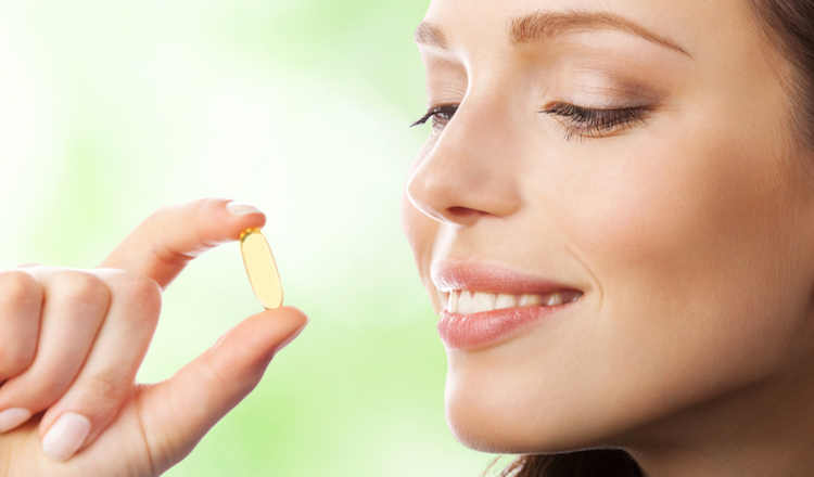 Young smiling woman with Omega 3 fish oil capsule, outdoor 440=