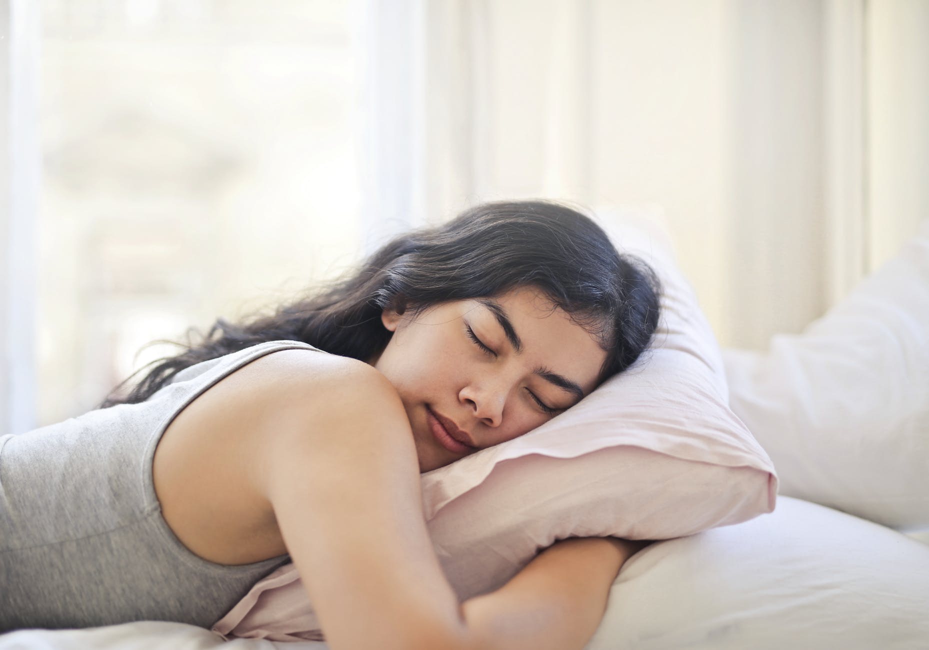 woman in gray tank top lying on bed