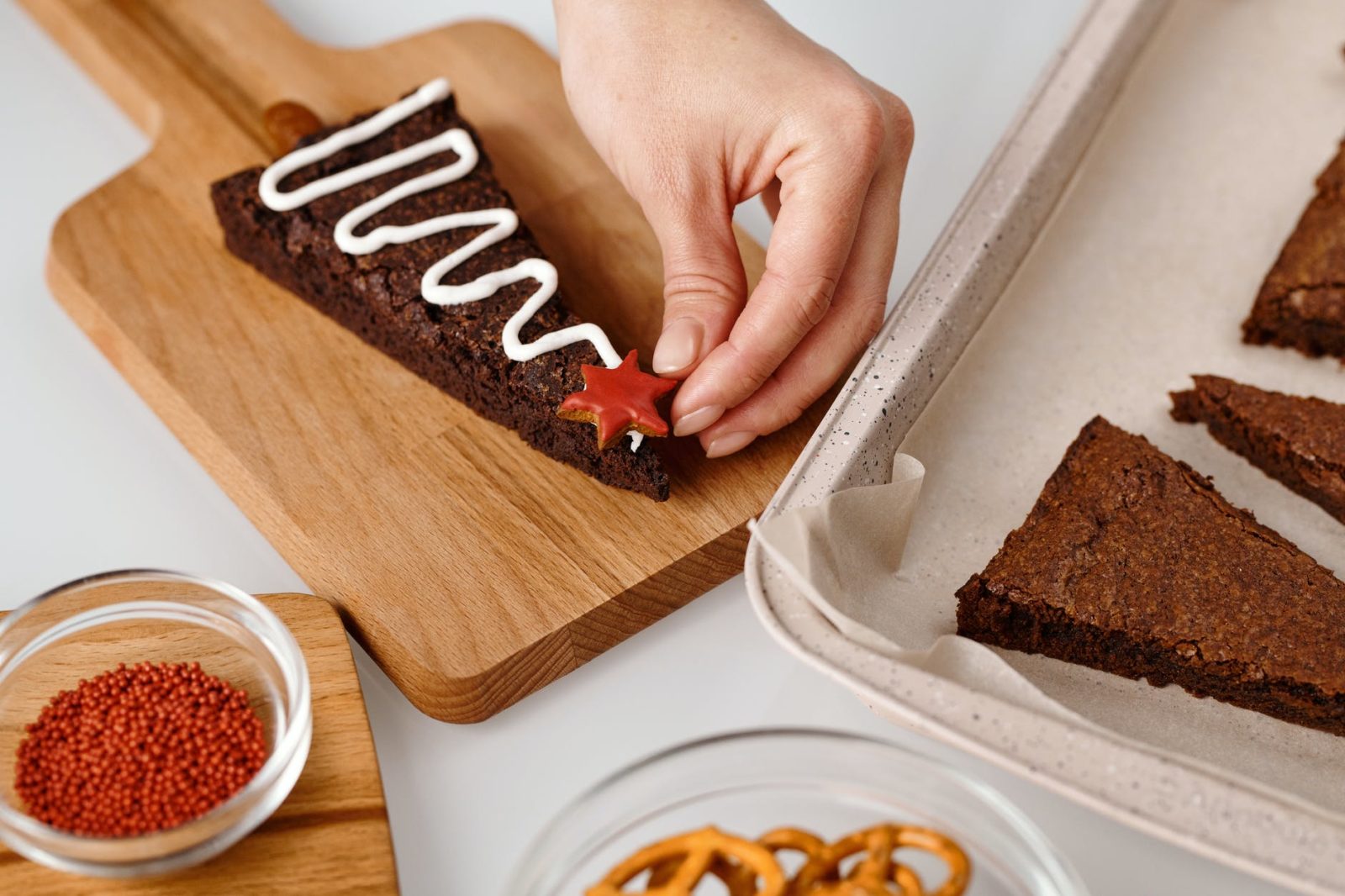 person decorating a triangle shaped brown cookie