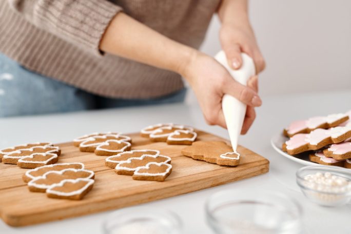 person decorating a christmas tree shaped cookies