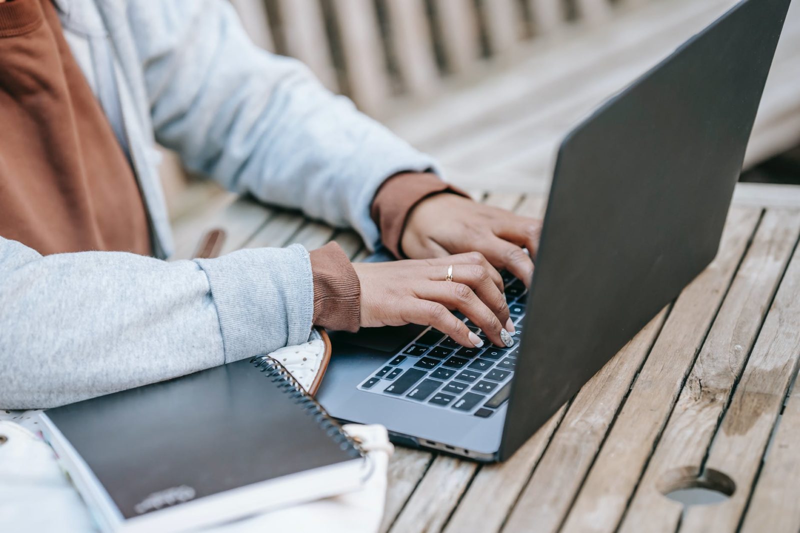 crop female entrepreneur typing on portable laptop while working in park