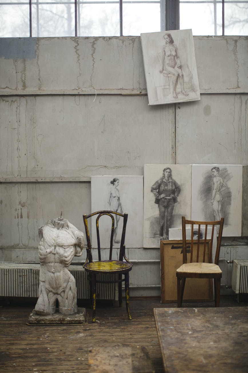 white concrete statue near brown wooden chairs