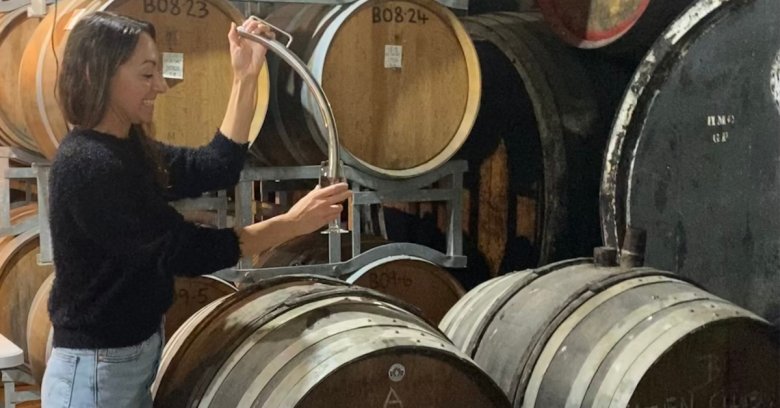 Girl drawing muscat out of a barrel at Pfeiffer Wines